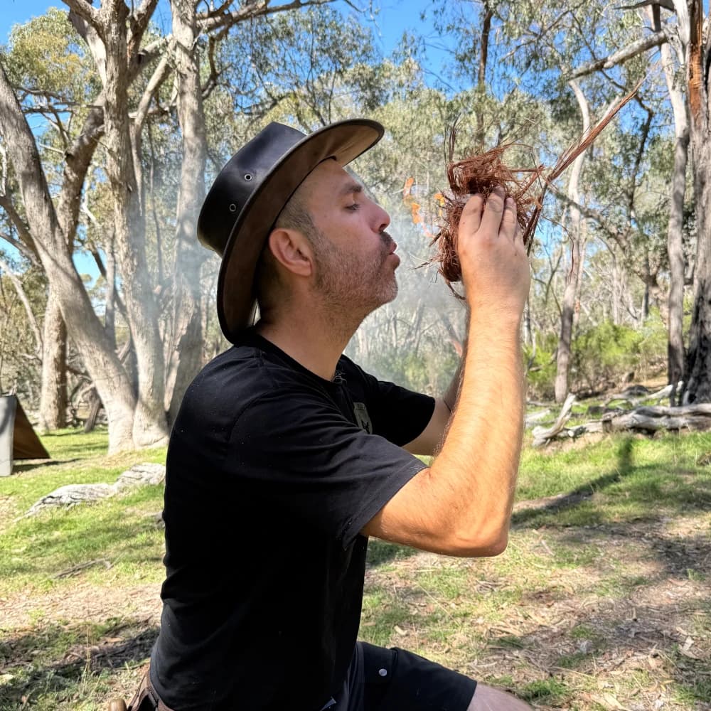 Photo of Michael Mersiades blowing tinder bundle
